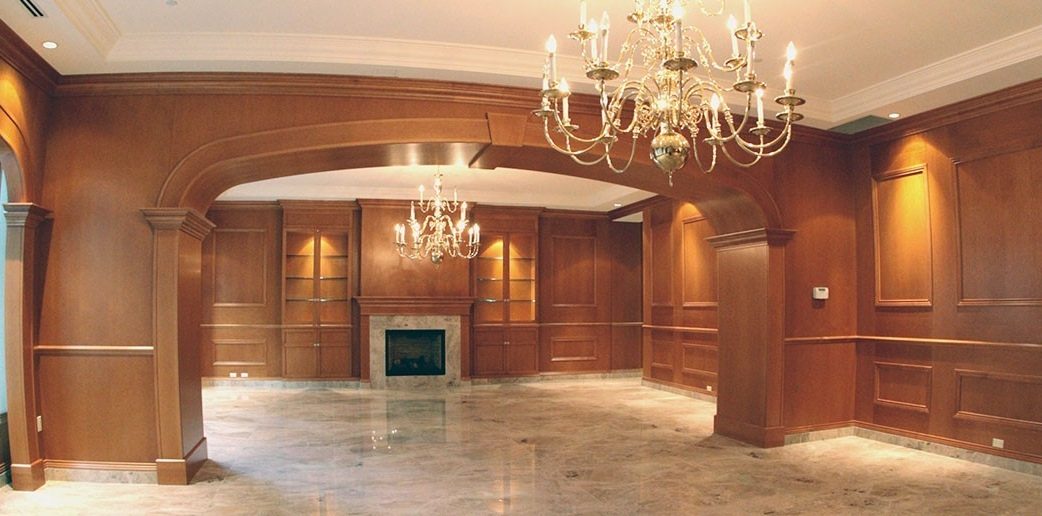Une salle entièrement lambrissée de bois : arche, foyer de marbre, lustres de laiton